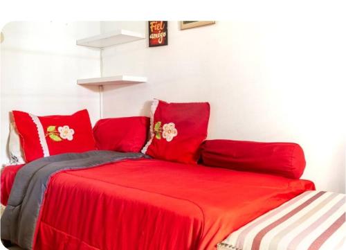 a red bed with red pillows in a room at Oasis Buenos Aires individual ó casal in Munro