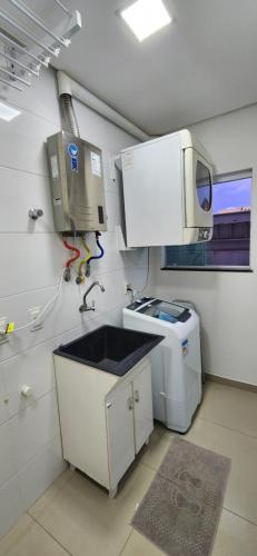 uma cozinha com um lavatório e uma máquina de lavar roupa em Casa Sunstay Garden com piscina em Bombinhas