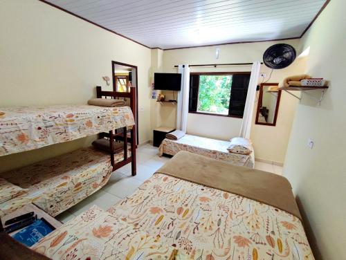 Habitación con 3 camas y ventana en Chalé da cachoeira - Ilhabela, en Ilhabela