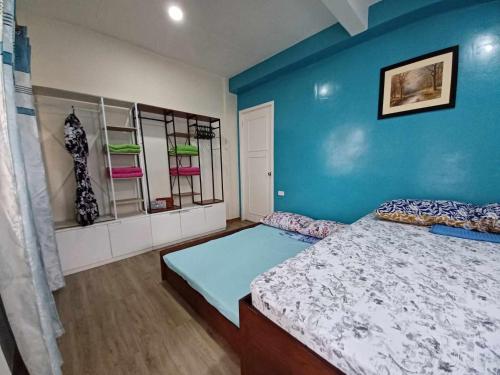 a bedroom with a bed and a blue wall at Cebu City 80sq Apartment near SM Seaside NuStar Ocean Park Dynamic Herb in San Roque