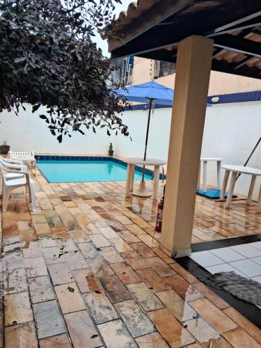 un patio con piscina, sillas y sombrilla en VILLAGE PÉ NA AREIA en Salvador