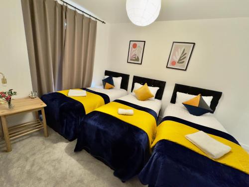 two beds in a room with yellow and blue sheets at Tower Bridge London, 2 Bedrooms, Reception, Kitchen, Parking in London