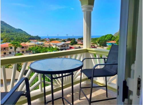 a balcony with a table and chairs and a view of the ocean at La Pelle in Soufrière