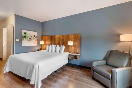 - une chambre avec un grand lit blanc et une chaise dans l'établissement Extended Stay America Premier Suites - Fredericksburg, à Fredericksburg