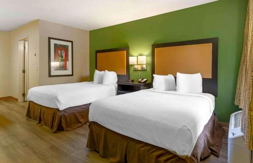 two beds in a hotel room with green walls at Extended Stay America Select Suites - Raleigh - RDU Airport in Morrisville