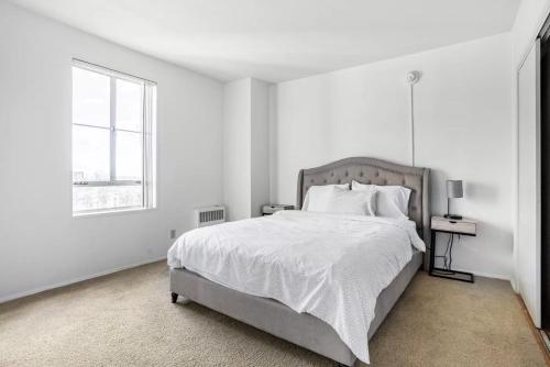 a white bedroom with a large bed and a window at Spacious 2 Bedroom 2 Bathroom Unit Great Location in Los Angeles