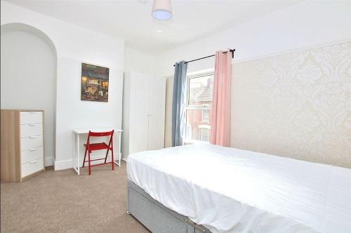 1 dormitorio con 1 cama blanca y 1 silla roja en Hood St en Kingsthorpe