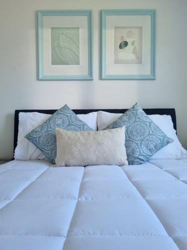 a white bed with pillows and two pictures on the wall at Hostal Chucaita Puerto Cisnes in Puerto Cisnes