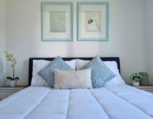 a white bed with blue and white pillows on it at Hostal Chucaita Puerto Cisnes in Puerto Cisnes