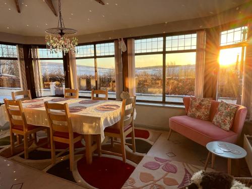 a dining room with a table and chairs and windows at Cowden Farmhouse, near Stonehaven. in Glenbervie