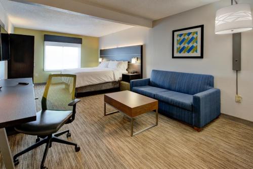 a hotel room with a bed and a couch and a chair at Holiday Inn Express & Suites Charlotte-Concord-I-85, an IHG Hotel in Concord