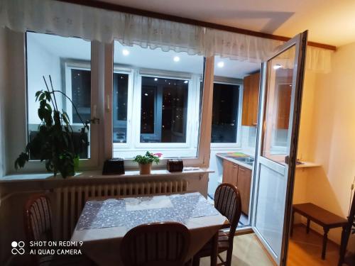 eine Küche und ein Esszimmer mit einem Tisch und Fenstern in der Unterkunft Apartman Viktor Sarajevo in Sarajevo
