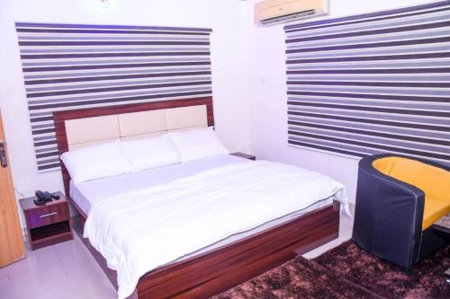 ein kleines Schlafzimmer mit einem Bett und einem gelben Stuhl in der Unterkunft Optimum Residence in Lagos