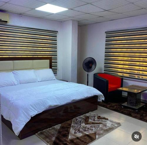 ein Schlafzimmer mit einem großen Bett und einem roten Stuhl in der Unterkunft Optimum Residence in Lagos