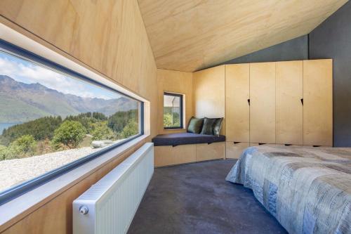 1 dormitorio con ventana grande y cama en Bivvy House Of The Year Winner, en Queenstown