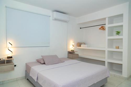 ein weißes Schlafzimmer mit einem Bett und zwei Lampen in der Unterkunft Javi’s Home in Cartagena de Indias
