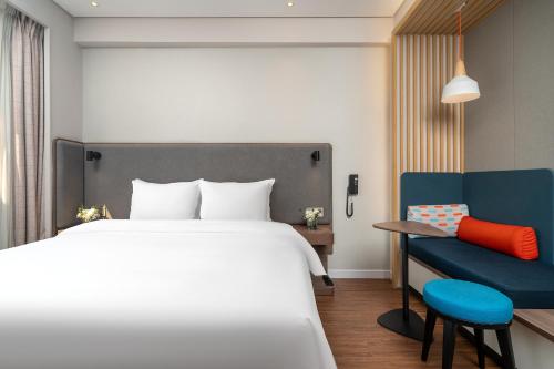 a bedroom with a large bed and a blue chair at Holiday Inn Express Xiamen Lushan -Shopping Center by IHG in Xiamen