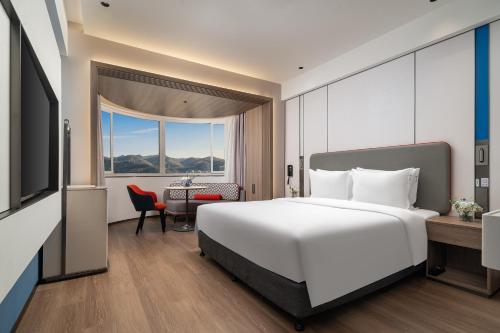a bedroom with a large white bed and a desk at Holiday Inn Express Xiamen Lushan -Shopping Center by IHG in Xiamen