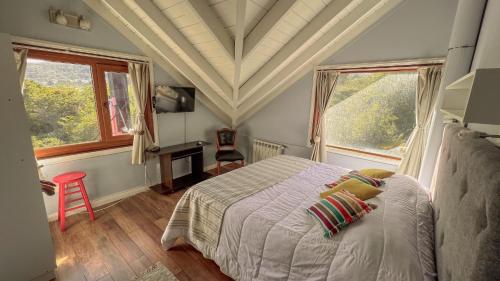 een slaapkamer met een bed en 2 ramen bij Villa de los Ñires in Ushuaia