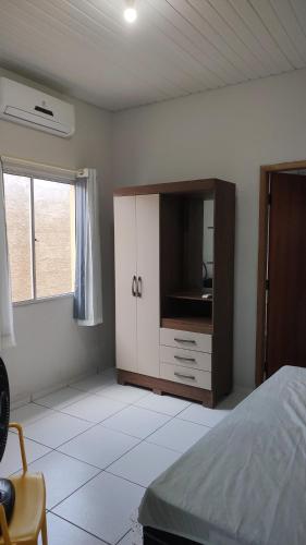 um quarto com uma cama e um armário com uma televisão em Casa Caminho da Alvorada em Parnaíba