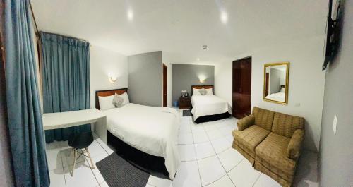 Habitación de hotel con 2 camas y sofá en Quinta San Carlos Hostel, en Ibarra