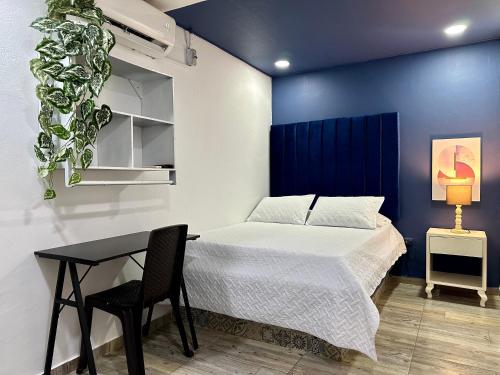 - une chambre avec un lit, une table et un mur bleu dans l'établissement Hotel Londres Real, à Valledupar