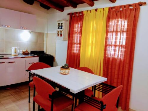 - une cuisine avec une table, des chaises rouges et des rideaux dans l'établissement dpto temporario, à Las Compuertas