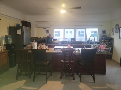 a kitchen with a bar with chairs around it at Penthouse across from the beach in La Piedra