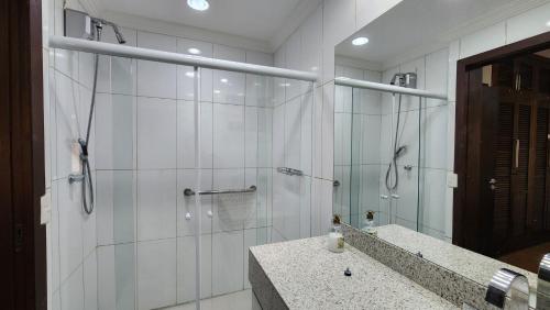 uma casa de banho com uma cabina de duche em vidro e um lavatório. em Apto no centro turístico Capivari (150m do Baden) em Campos do Jordão