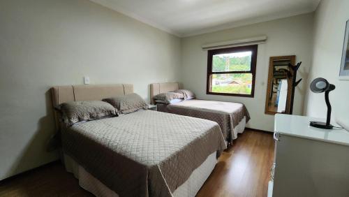 - une petite chambre avec 2 lits et une fenêtre dans l'établissement Apto no centro turístico Capivari (150m do Baden), à Campos do Jordão