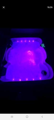 a purple tub with pink lights in a dark room at Superbe appartement avec jacuzzi, sauna et hammam, proche de Paris in Châtillon
