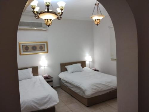 two beds in a room with a mirror at Qurban Apartment in Al ‘Awālī