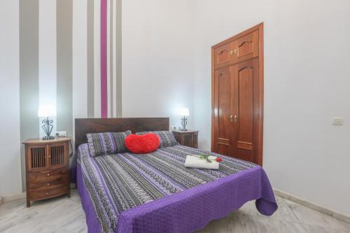 ein Schlafzimmer mit einem lila Bett mit zwei roten Kissen in der Unterkunft GALINDO CENTER PREMIUM SUITES, Free Parking in Sevilla