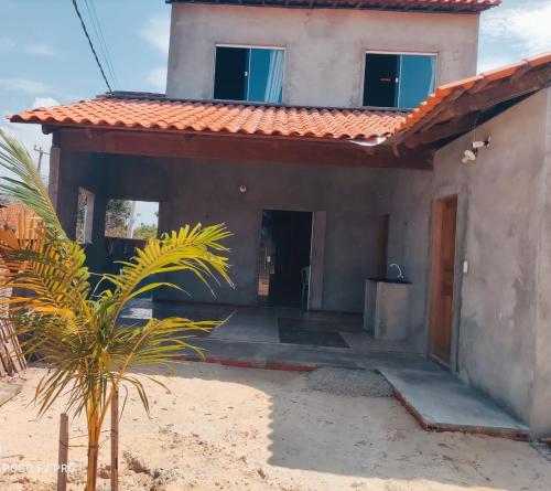 a house with a palm tree in front of it at Casa Luz / Beira Mar in Tutóia