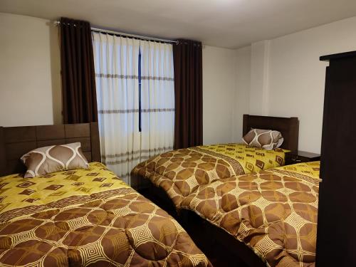 ラパスにあるDepartamentos a su altura en La Pazのベッドルーム1室(黄色と茶色の毛布を使用したベッド2台付)