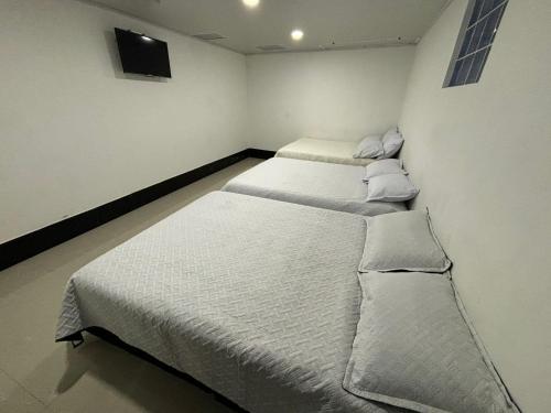 2 Einzelbetten in einem Zimmer mit einem TV in der Unterkunft HOTEL TUNJA ALEJANDRIA in Tunja