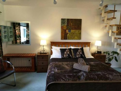 um quarto com uma cama grande e uma escada em Amazing Lakeview Loft em Rotorua