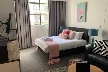 a hotel room with a bed and a couch at Cute Heritage Studio , Pools and Gym! in Auckland