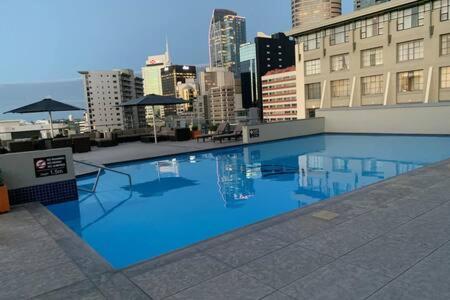 a large blue swimming pool on top of a building at Cute Heritage Studio , Pools and Gym! in Auckland