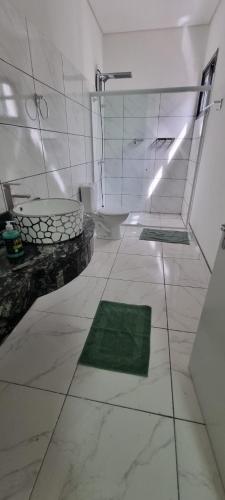 a white bathroom with a toilet and a green rug at Iguassu Jungle Hotel pousada in Foz do Iguaçu