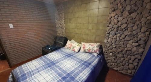 1 dormitorio con cama y pared de piedra en Alquiler playa Quequén, Necochea Buenos Aires en Quequén