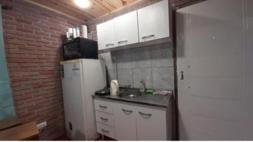 una pequeña cocina con fregadero y nevera. en Alquiler playa Quequén, Necochea Buenos Aires en Quequén