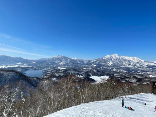 a group of people on a snow covered slope with mountains at マウンテンリゾート・マルガンタ Marganta in Madarao Kogen