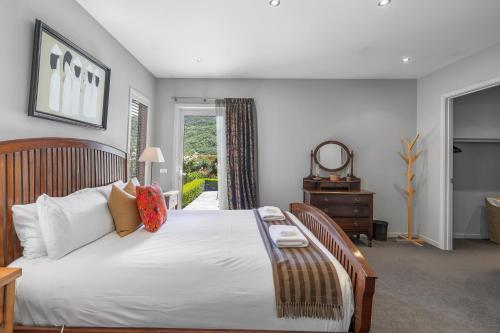 a bedroom with a large white bed and a window at Elite Holiday Homes Queenstown - Arrowbrae in Arrowtown