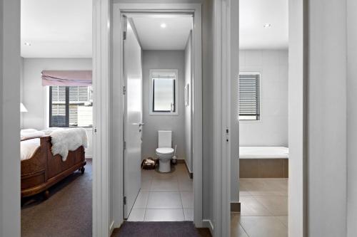 a bedroom with a bed and a bathroom with a toilet at Elite Holiday Homes Queenstown - Arrowbrae in Arrowtown