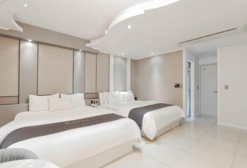 two beds in a hotel room with white at Renaissance Hotel Pohang in Pohang