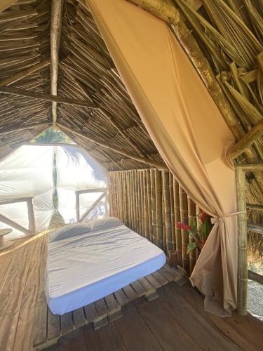 a bed in a thatched room with a window at Freeland Eco Hostel in Santa Marta