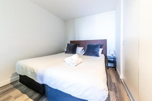 a bedroom with a large white bed with blue pillows at Aura2107, CBD Entire 2 Bedroom Apartment with Balcony and Stunning Yarra River Views in Melbourne