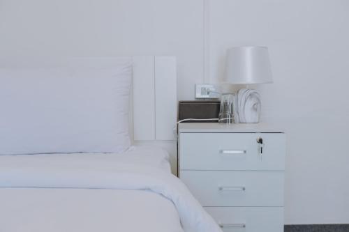 a white bedroom with a bed and a microwave at Blue Carina Hotel - SHA Plus in Phuket Town