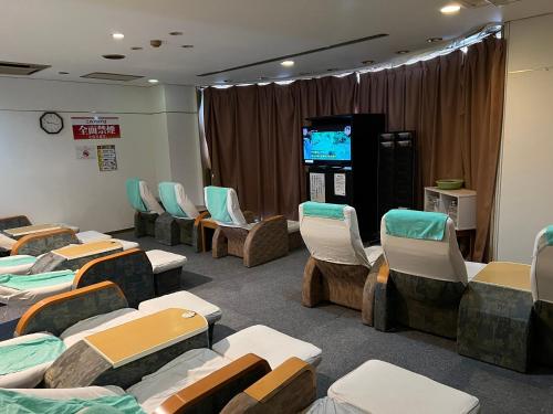 a waiting room with chairs and a video screen at 男性専用サウナ&カプセル Men Only Capsule Room & Sauna, Bathhouse ミナミ下北沢 Minami Shimokitazawa in Tokyo